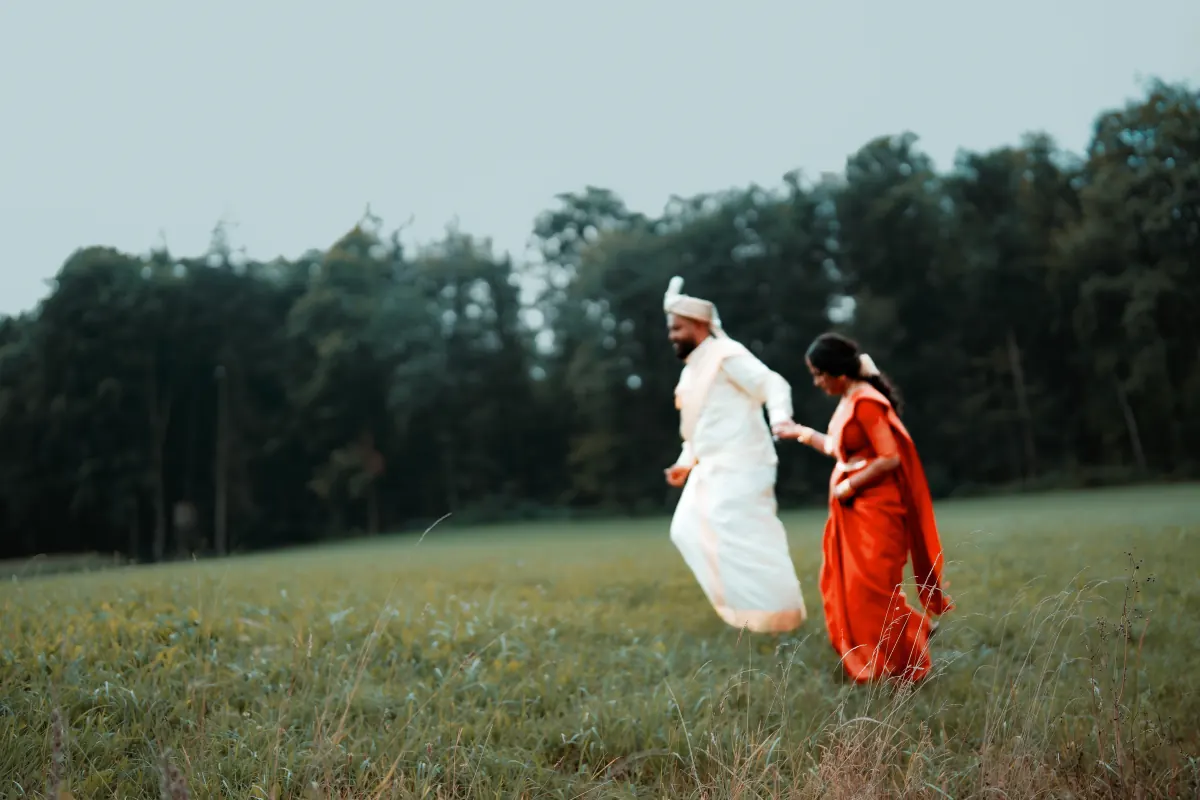 A couple running together through a meadow