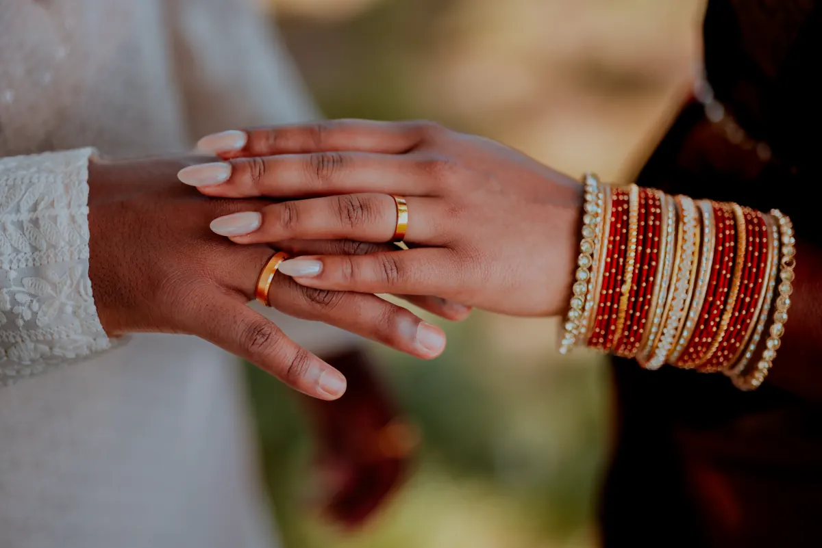 Two hands resting together, both wearing wedding rings